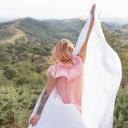 Frau mit rosa Kleid von hinten in der Natur weißes großen Leintuch in der hand welches im wind weht