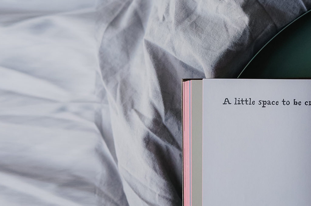 ein angeschlagenes Journal liegt im Bett auf dem Papier steht a little space to be creative