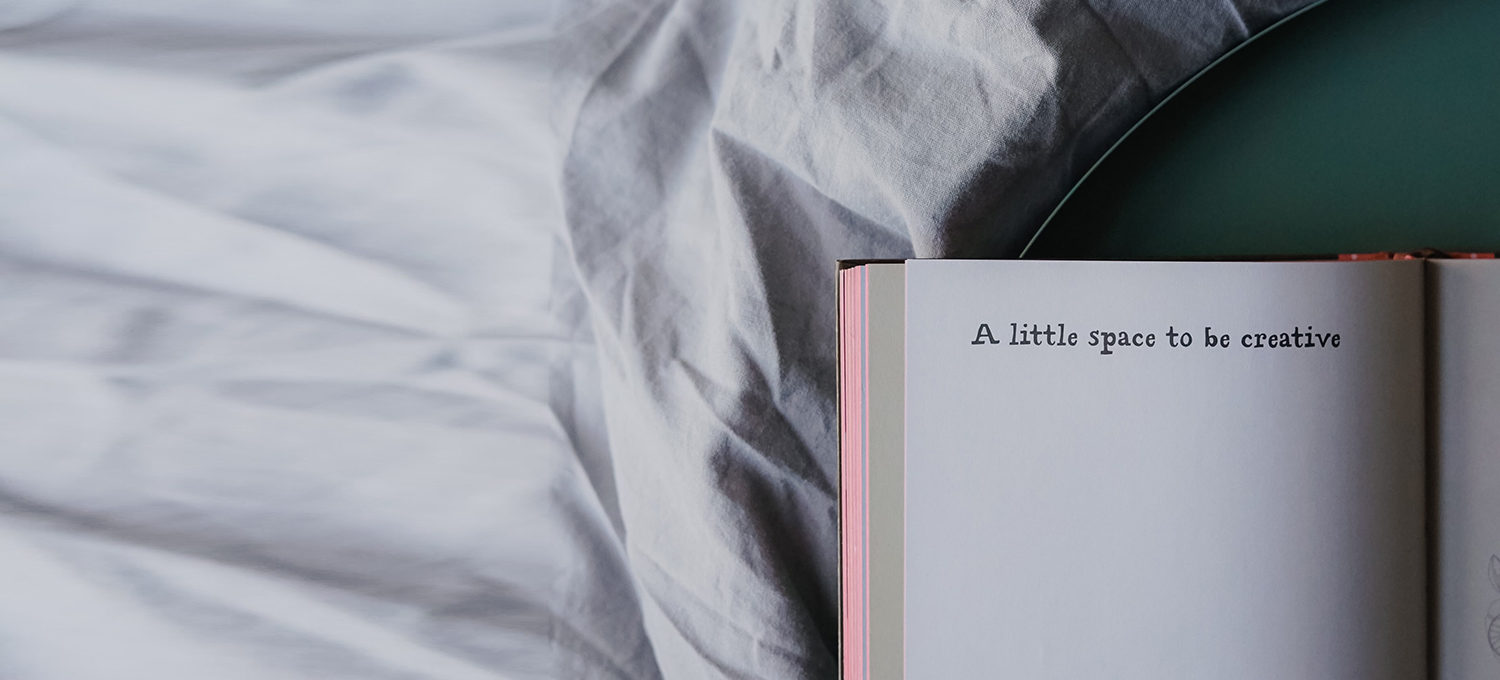 ein angeschlagenes Journal liegt im Bett auf dem Papier steht a little space to be creative