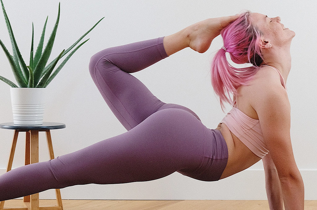 Frau mit pinken haaren im Bett scorpion fortgeschrittene yoga pose