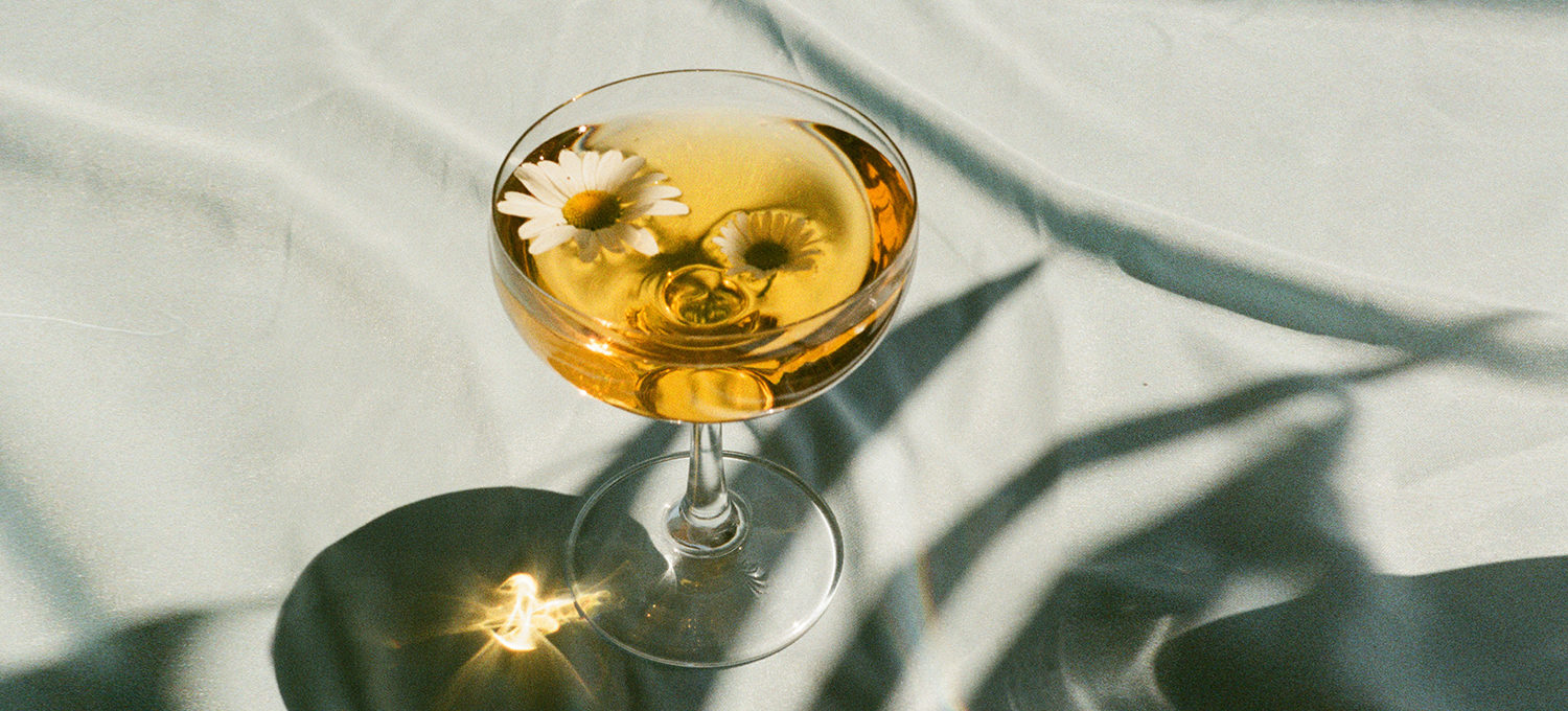 ein drink mit einer Blume im glas steht auf einem Türkisen Stoff