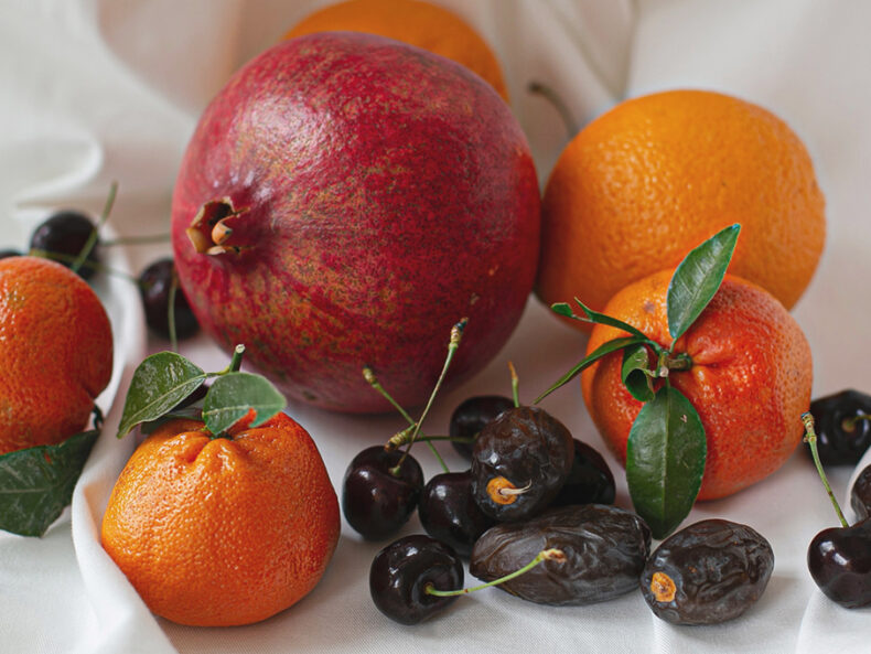 Stillleben eines Granatapfels mit Mandarinen, Kirschen und Datteln