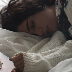 Frau in Wollpulli schlafend im Bett